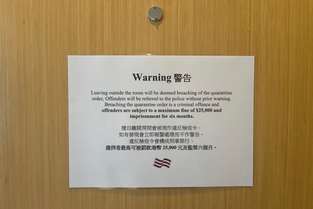A sign posted on the hotel room door warns guests not to leave the room. Credit:Caroline Chen/ProPublica