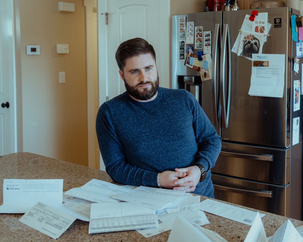 Elliot Malin at his home in Reno, Nevada, with bills he was sent after donating his kidney to his cousin Credit:Andri Tambunan, special to ProPublica