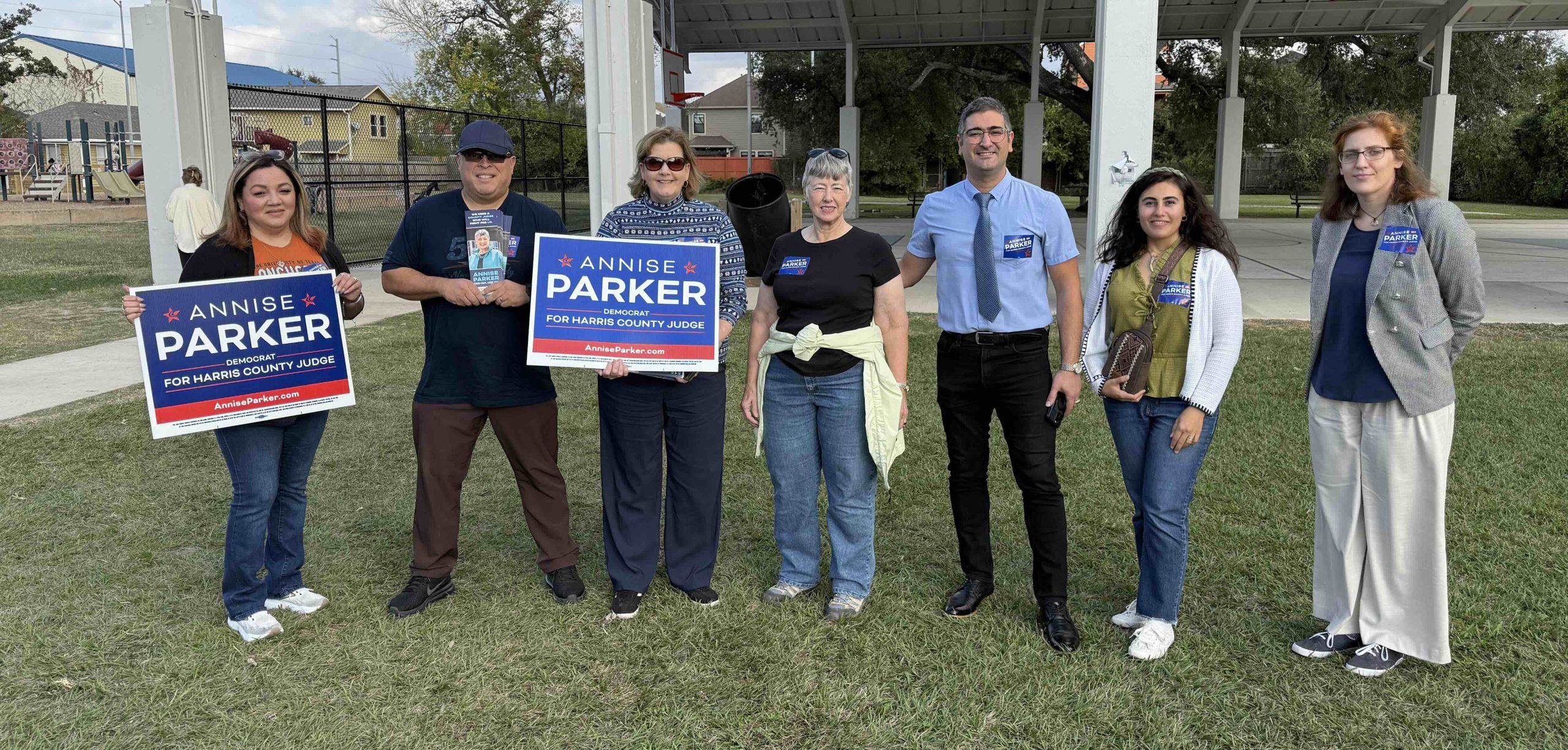 Un grupo de personas sosteniendo carteles de campaña de Annise Parker en un parque.