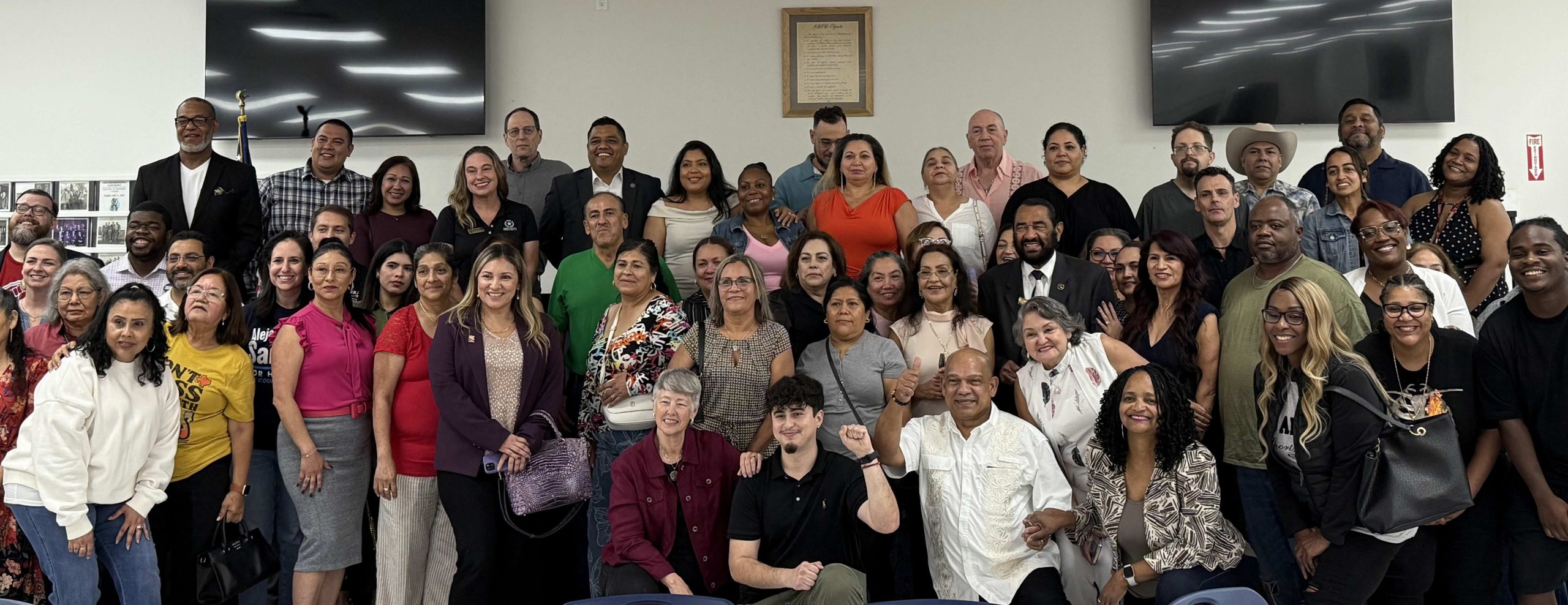 Grupo diverso de personas posando juntas en un evento comunitario, sonriendo y mostrando unidad.