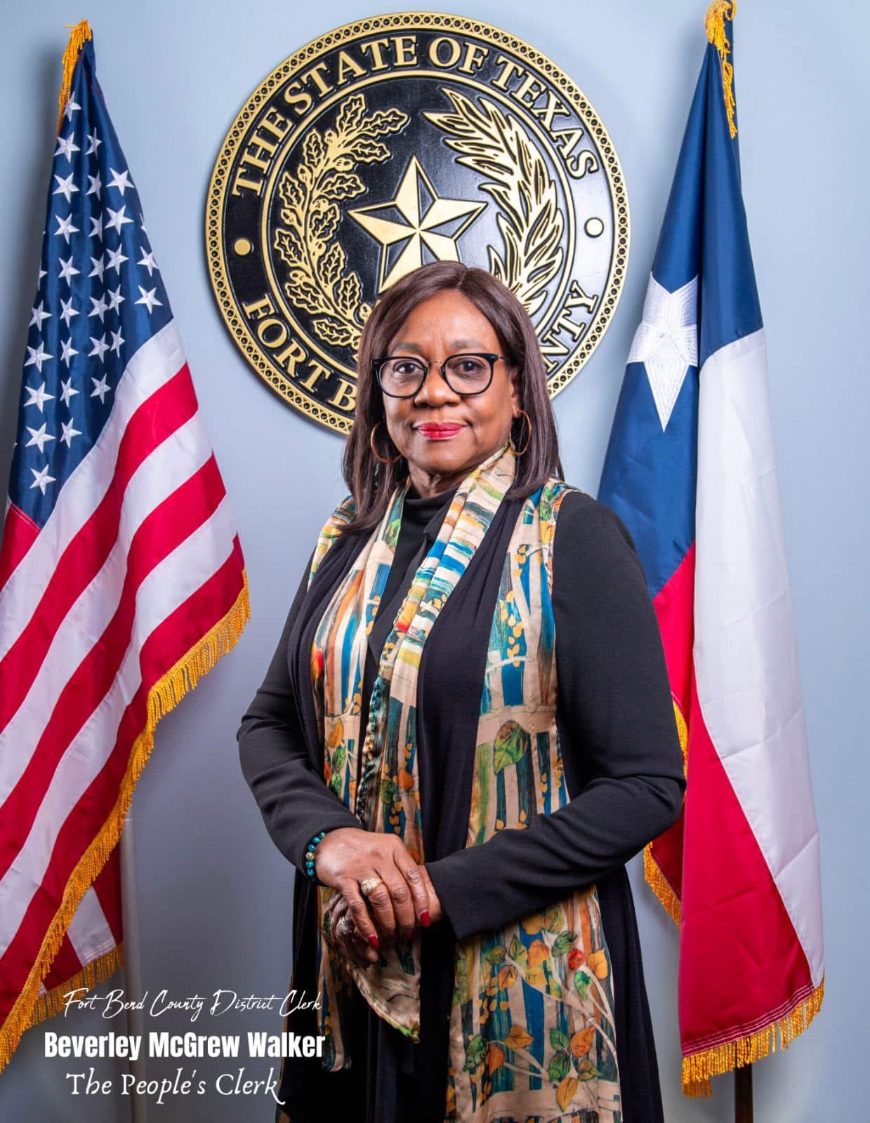 Retrato de una mujer en un ambiente gubernamental, con banderas de EE. UU. y Texas de fondo, representando el compromiso con la comunidad hispanohablante.