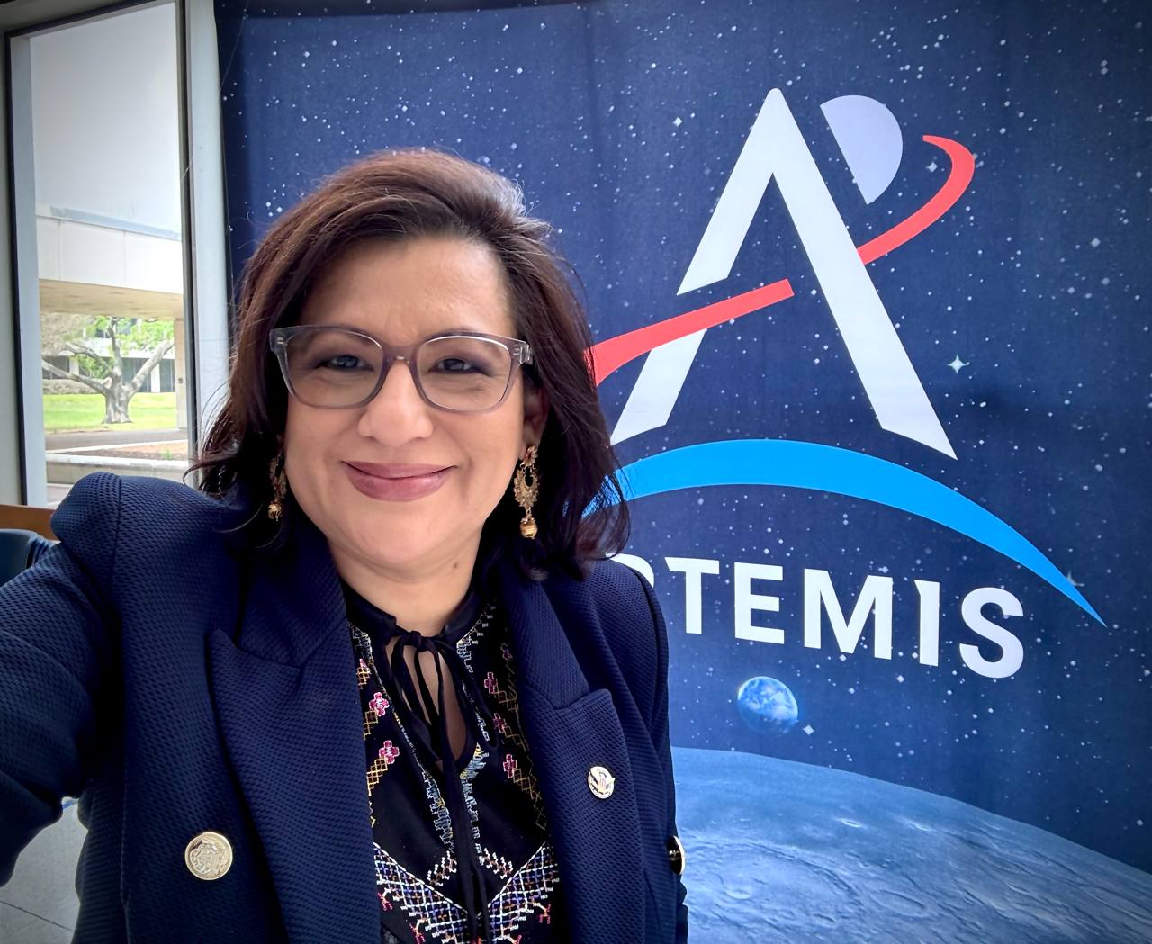 Daysi Marin, directora de Se Habla Español News, frente al banner oficial del programa Artemis de la NASA en el Johnson Space Center