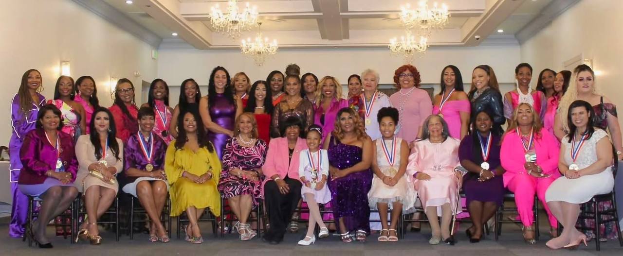 Foto grupal grande de todas las mujeres reconocidas con medallas en evento formal con candelabros