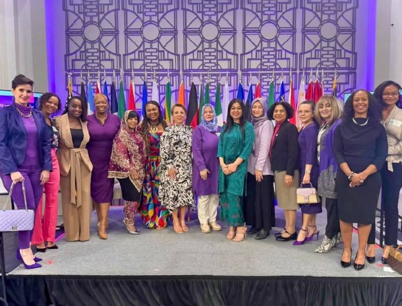 Grupo de mujeres diversas frente a banderas internacionales en evento multicultural