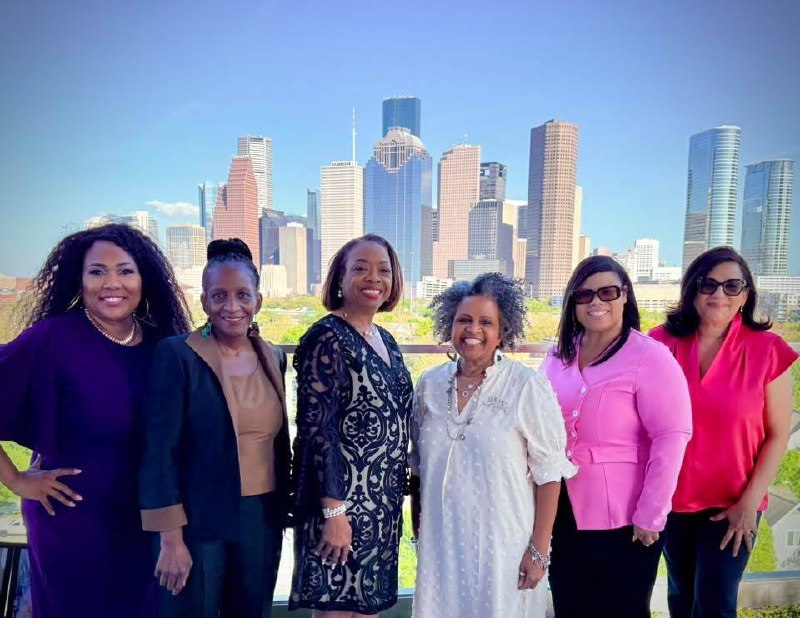 Grupo de 6 mujeres líderes incluyendo Daysi Marin (blusa rosa/roja) con skyline de Houston de fondo