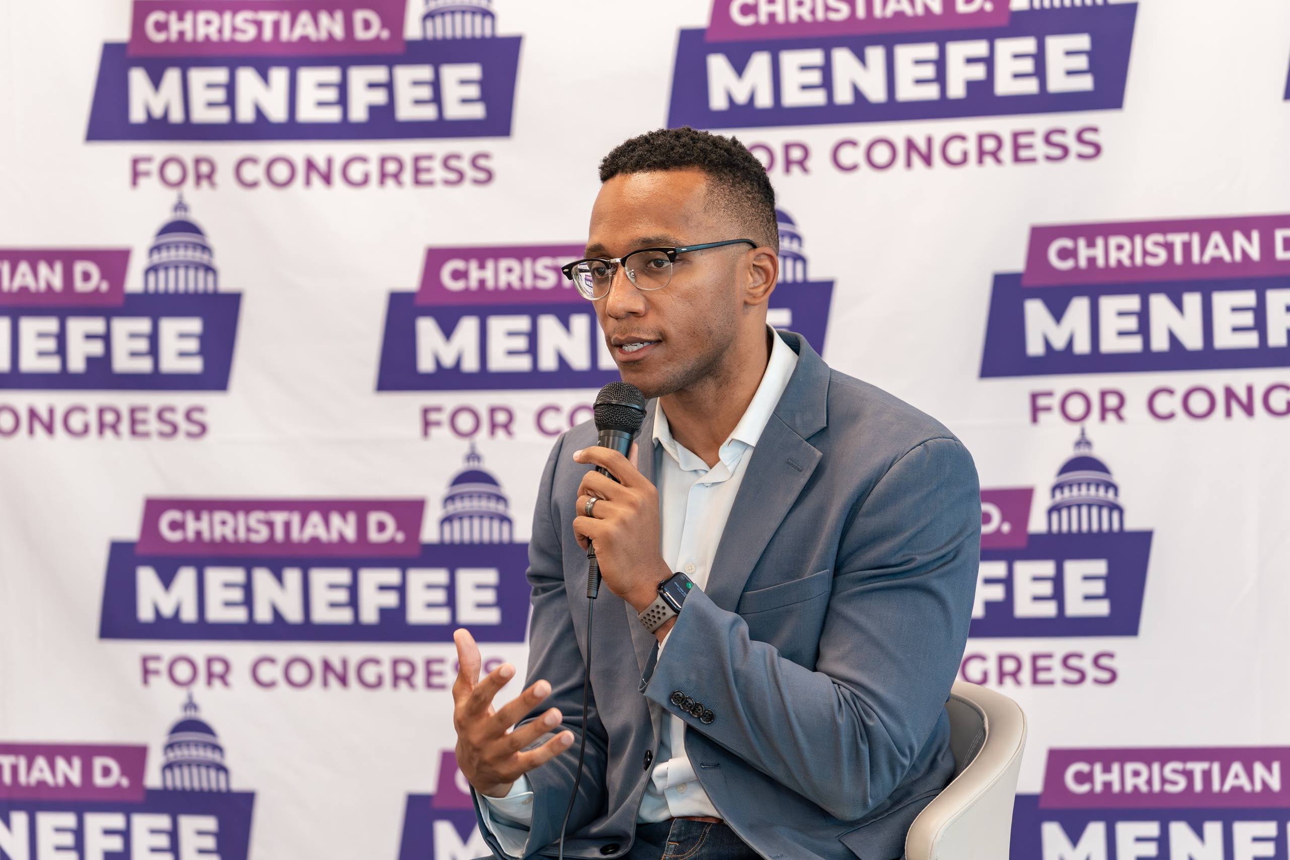 Christian Menefee hablando con micrófono en evento de campaña al Congreso