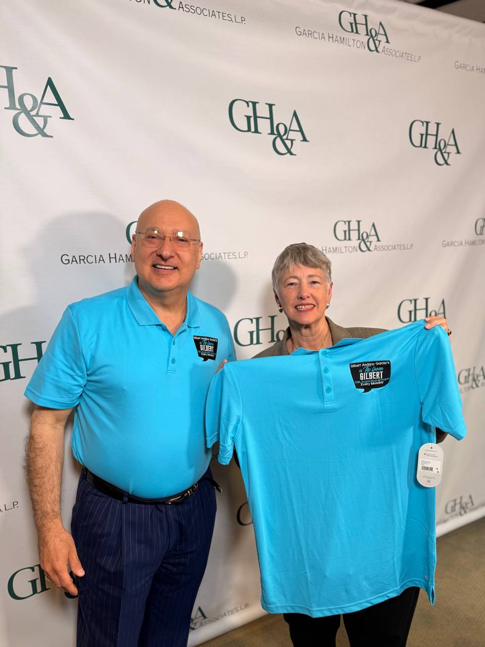 Gilbert y Annise en Garcia Hamilton and Associates con camisetas azules del podcast