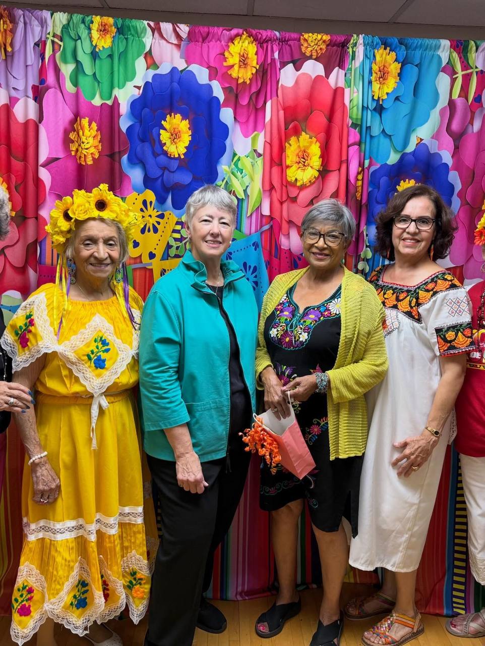 Annise Parker con senoras en vestidos mexicanos coloridos frente a flores - celebracion 5 de mayo