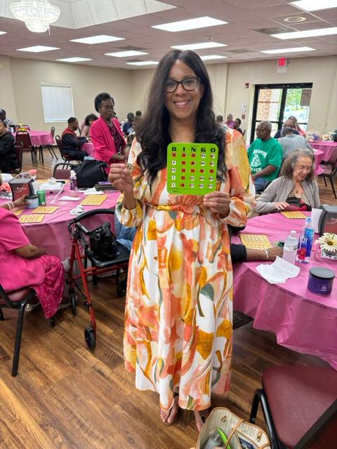 Rachelle Carter en evento de bingo para personas mayores sosteniendo una tarjeta de bingo