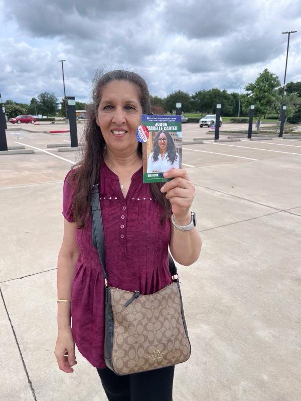 Mujer sosteniendo tarjeta de campana de Rachelle Carter con sticker I Voted